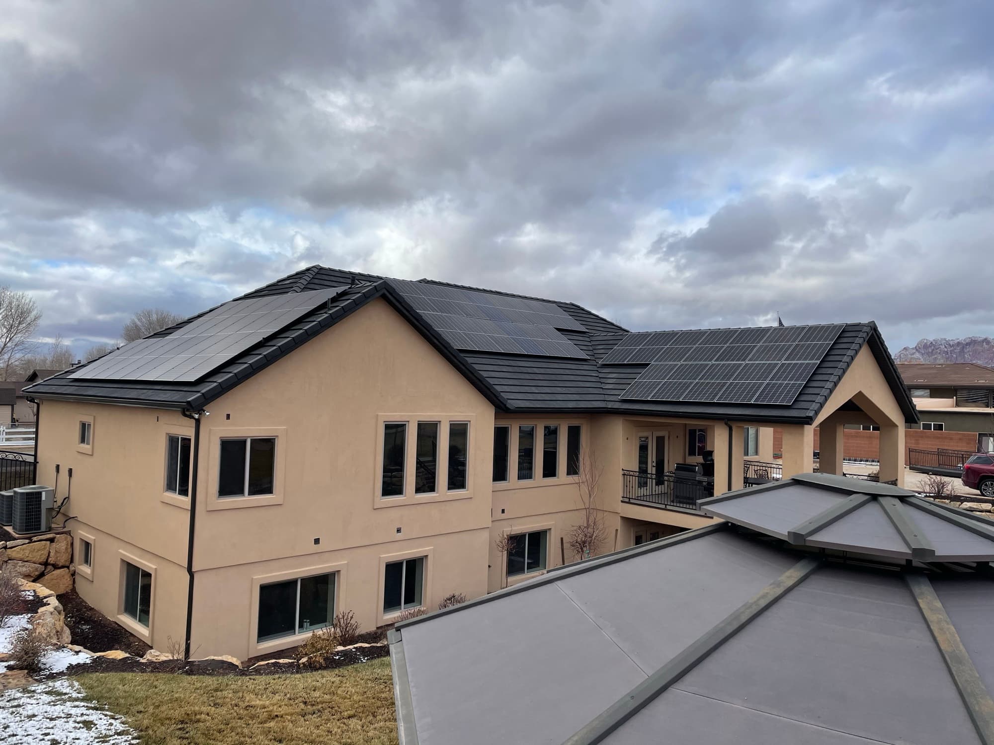 Custom home with rooftop solar panels against Utah mountain backdrop